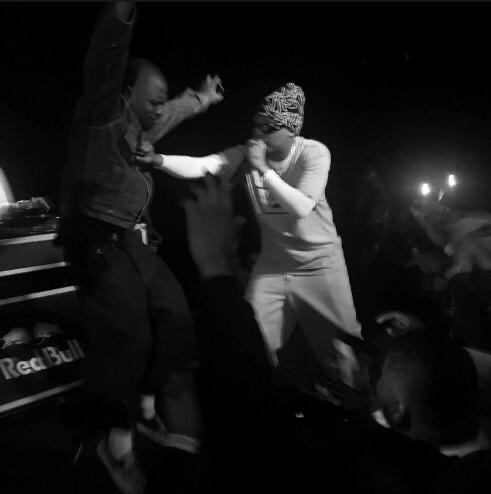 Black-and-white performance moment between two artists at the edge of the stage