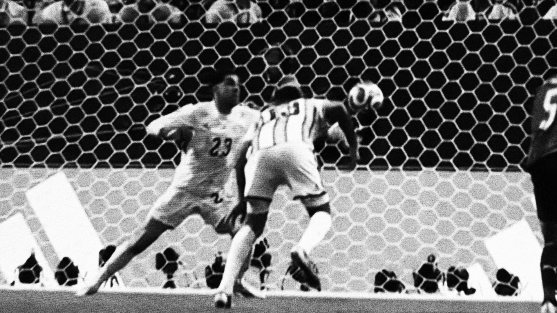 Two defenders contesting the ball in front of the goal net