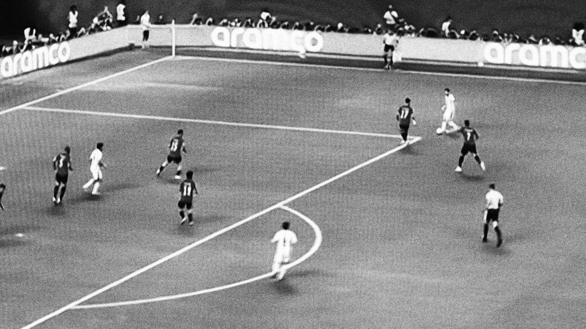 Midfield play unfolding under stadium floodlights