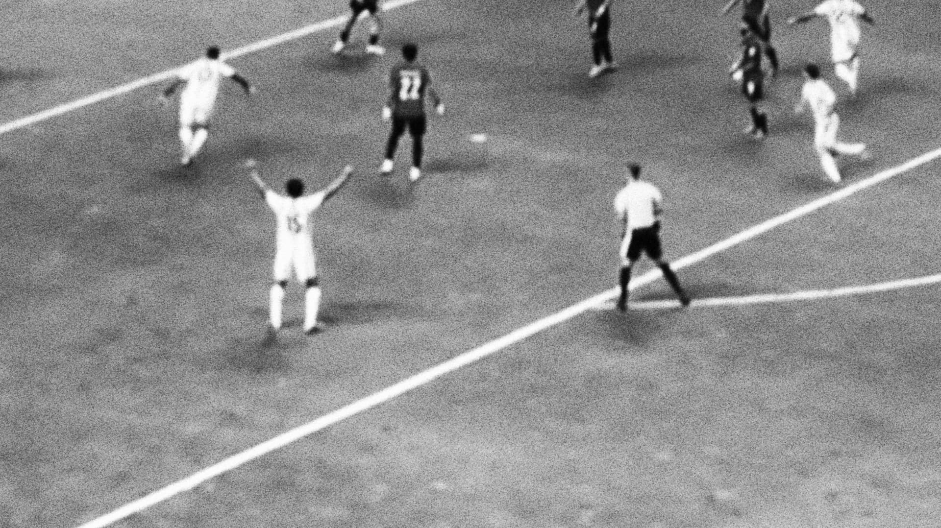 A player celebrating with arms raised as the game continues