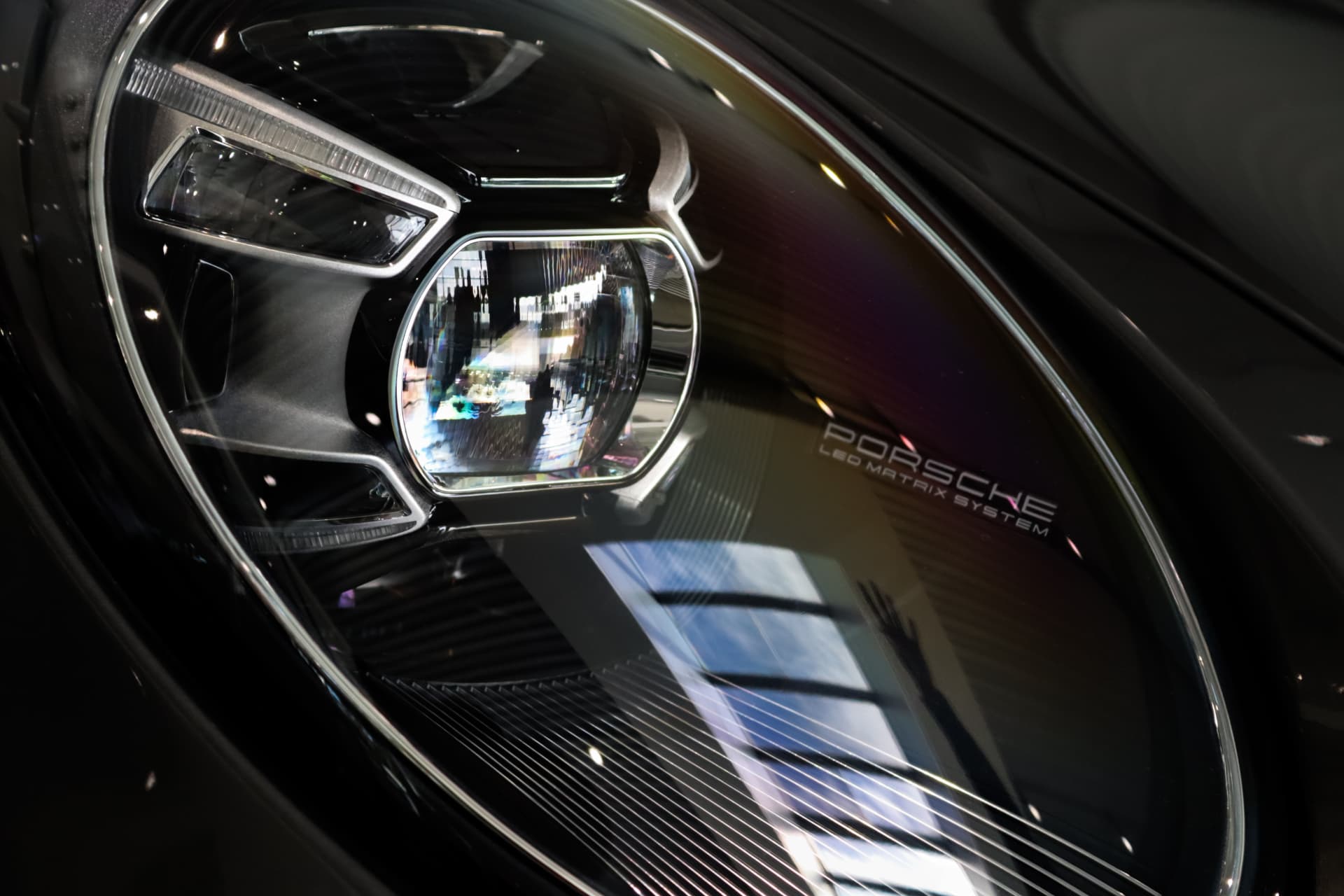 Close-up of a Porsche LED Matrix headlight with city reflections in the glass